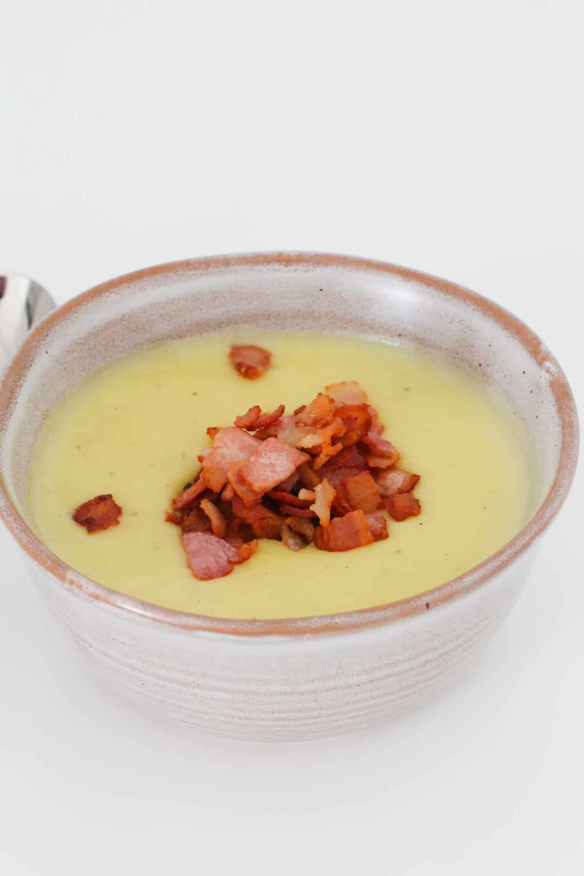 A round bowl filled with potato and leek soup with bacon on top.