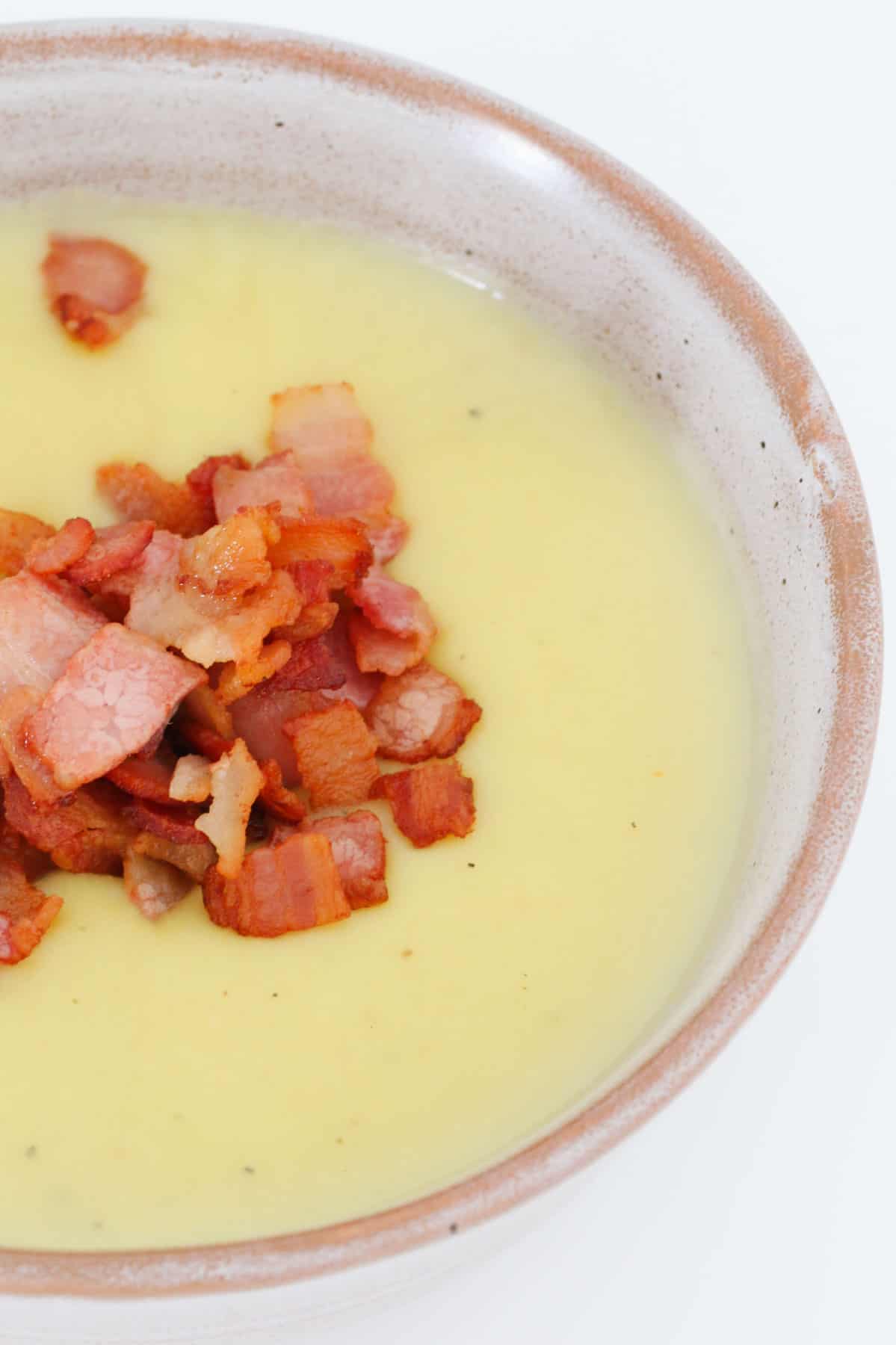 A creamy soup in a bowl topped with bacon.
