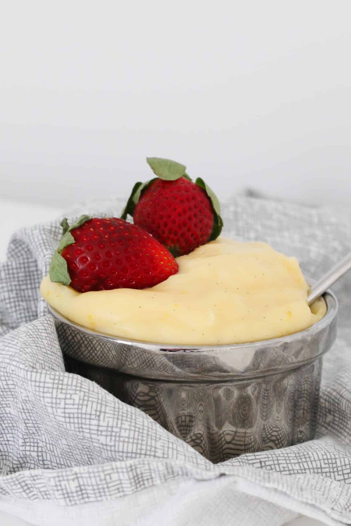 Strawberries on top of a silver bowl filled with custard.