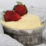Strawberries on top of vanilla custard in a silver bowl.