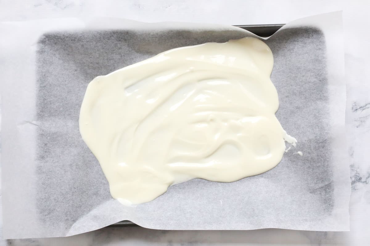 Melted white chocolate on a baking tray.