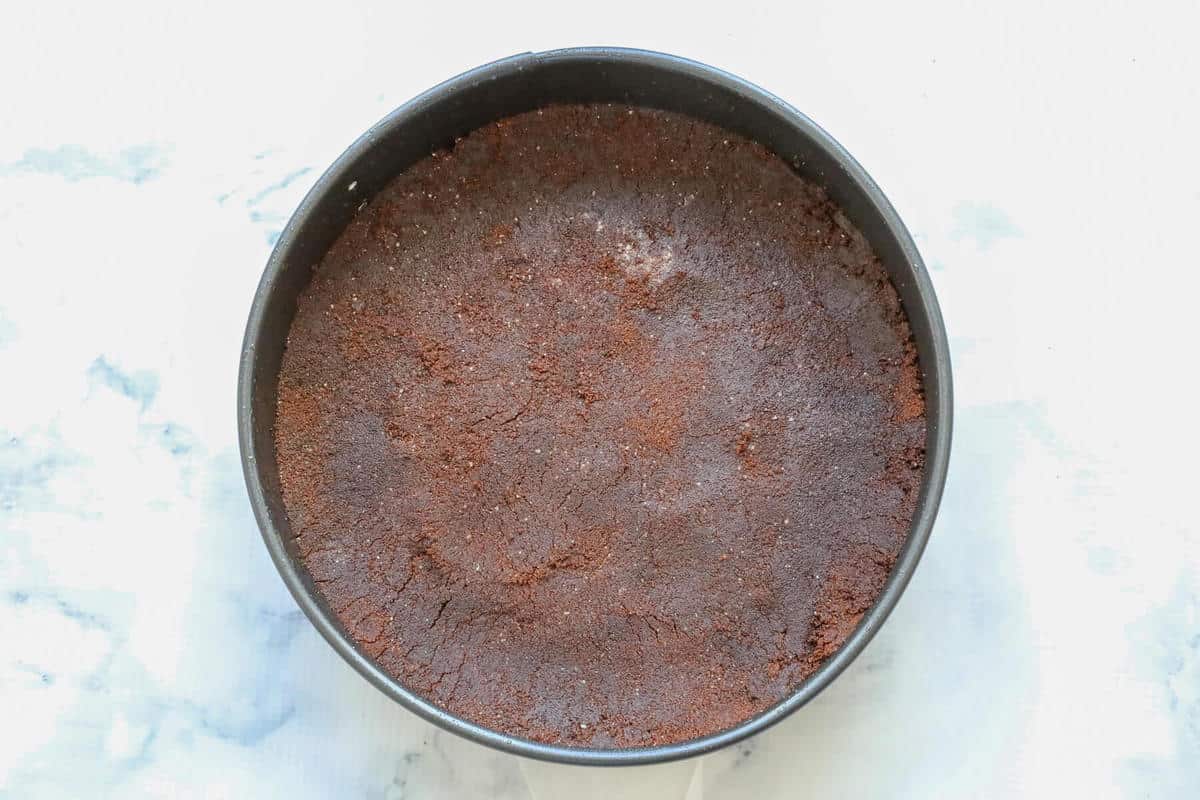 Chocolate biscuit crumbs pressed into a tin.