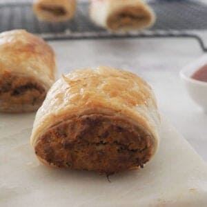 close up of a vegetarian sausage roll on a white marble tray.