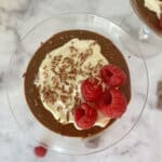 overhead view of chocolate mousse in a glass topped with cream and raspberries