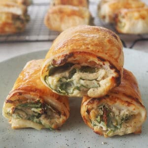 three thermion spinach and ricotta rolls on a green speckled plate.