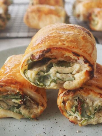 three thermion spinach and ricotta rolls on a green speckled plate.
