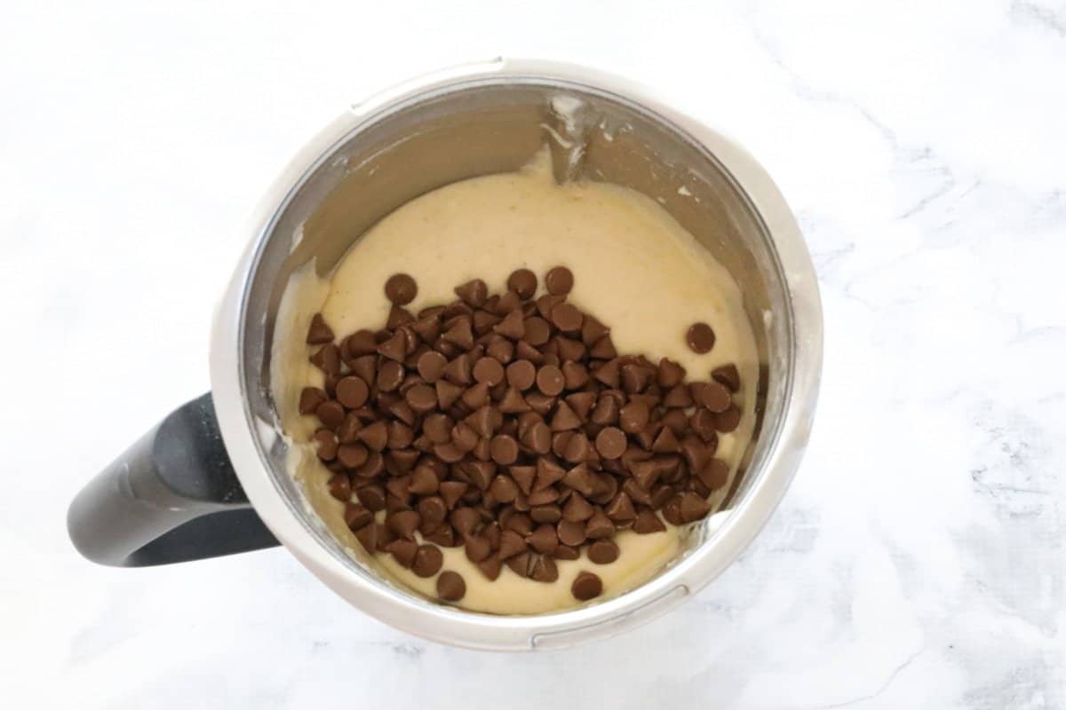 Chocolate chips on top of muffin mixture in a Thermomix bowl.
