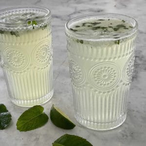 Two Thermomix Mojitos in decorative glasses on a marble top.