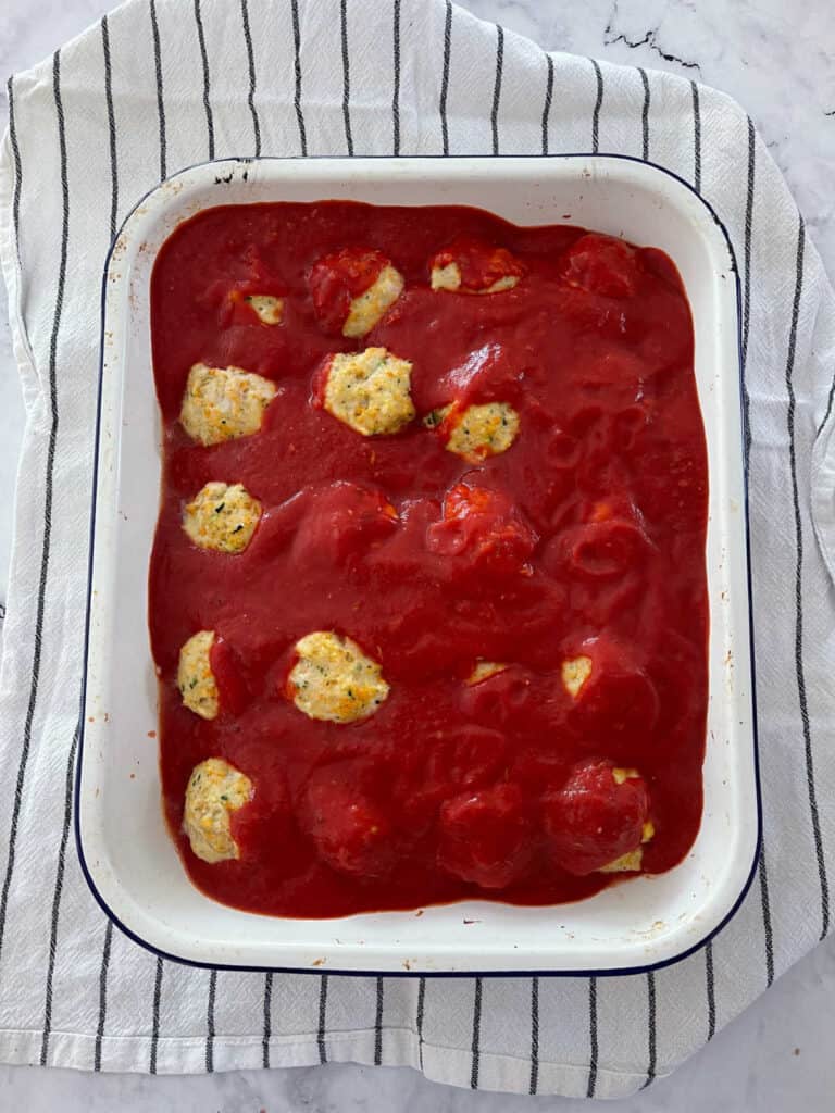 chicken parma balls in baking dish with sauce over the top.
