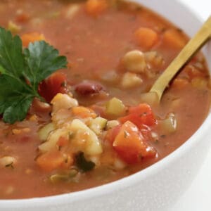 A spoon in a bowl of vegetable soup.