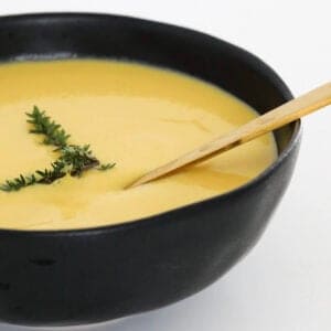 A gold soup in a black bowl filled with soup.