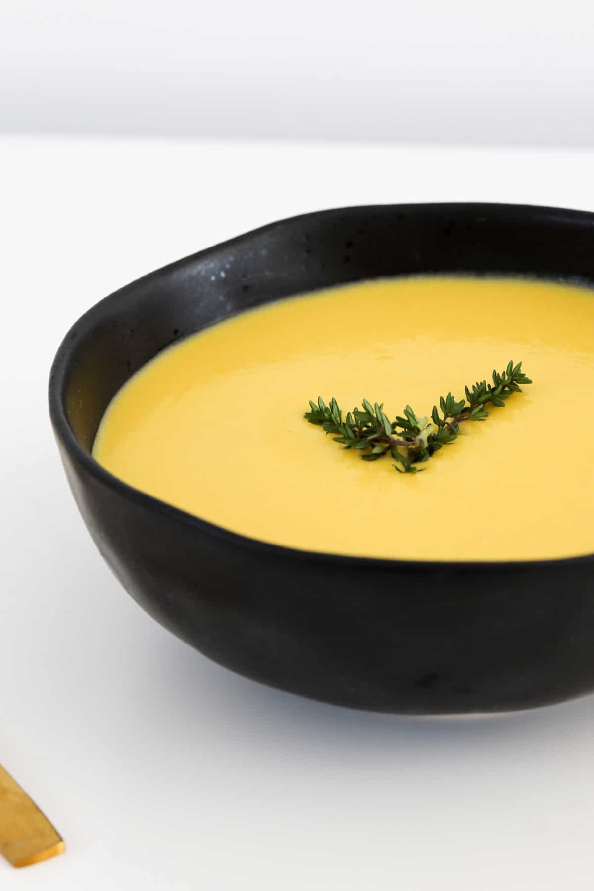 A creamy yellow soup in a black bowl.