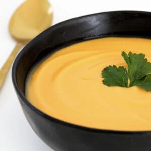 Creamy pumpkin and sweet potato soup in a black bowl.