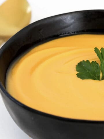 Creamy pumpkin and sweet potato soup in a black bowl.
