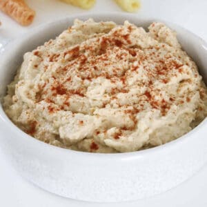 A bowl of hummus with paprika sprinkled on top.