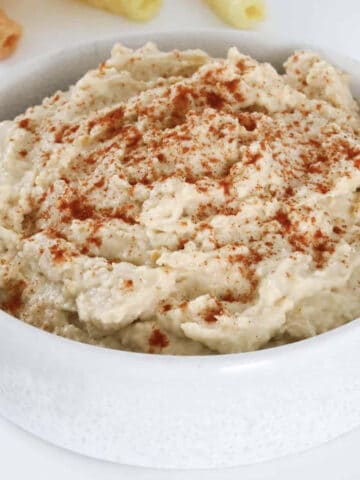 A bowl of hummus with paprika sprinkled on top.
