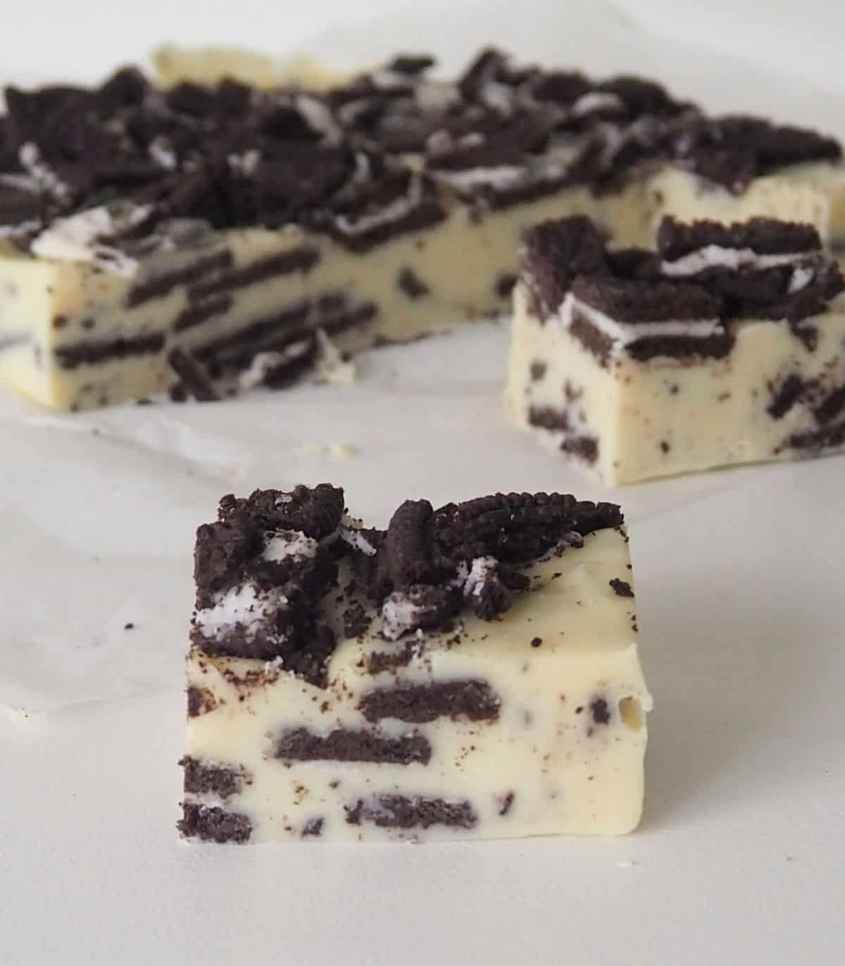 side view of slices of Oreo fudge on a piece of white baking paper and white bench top.