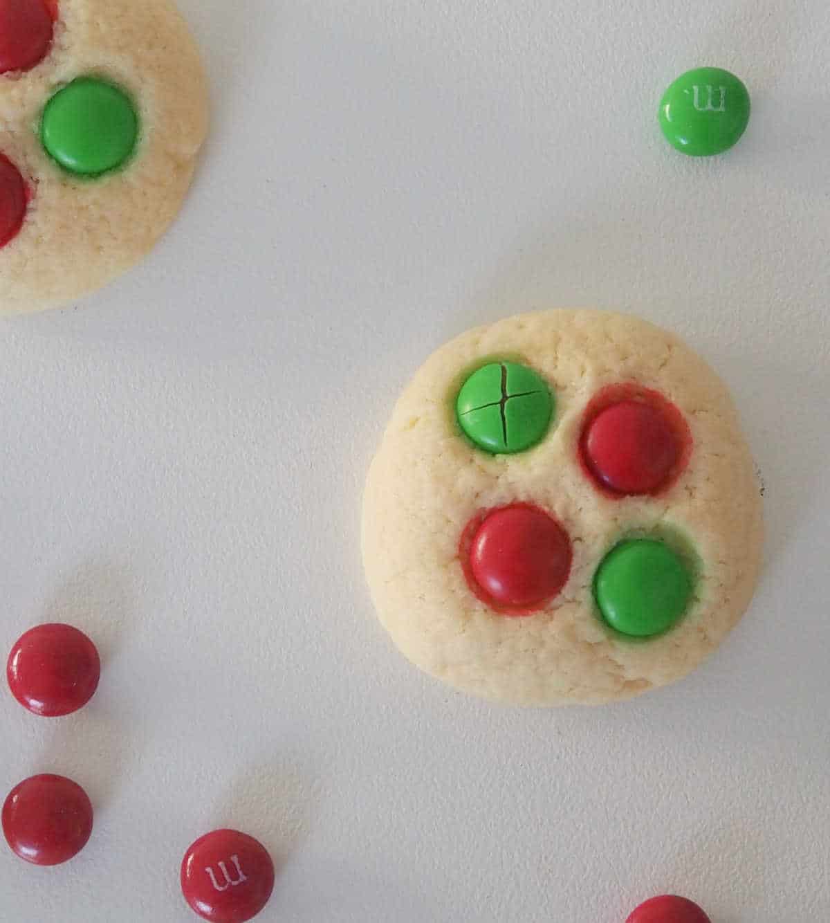 overhead of Thermomix Christmas Biscuits on a white background with red and green m&Ms around.