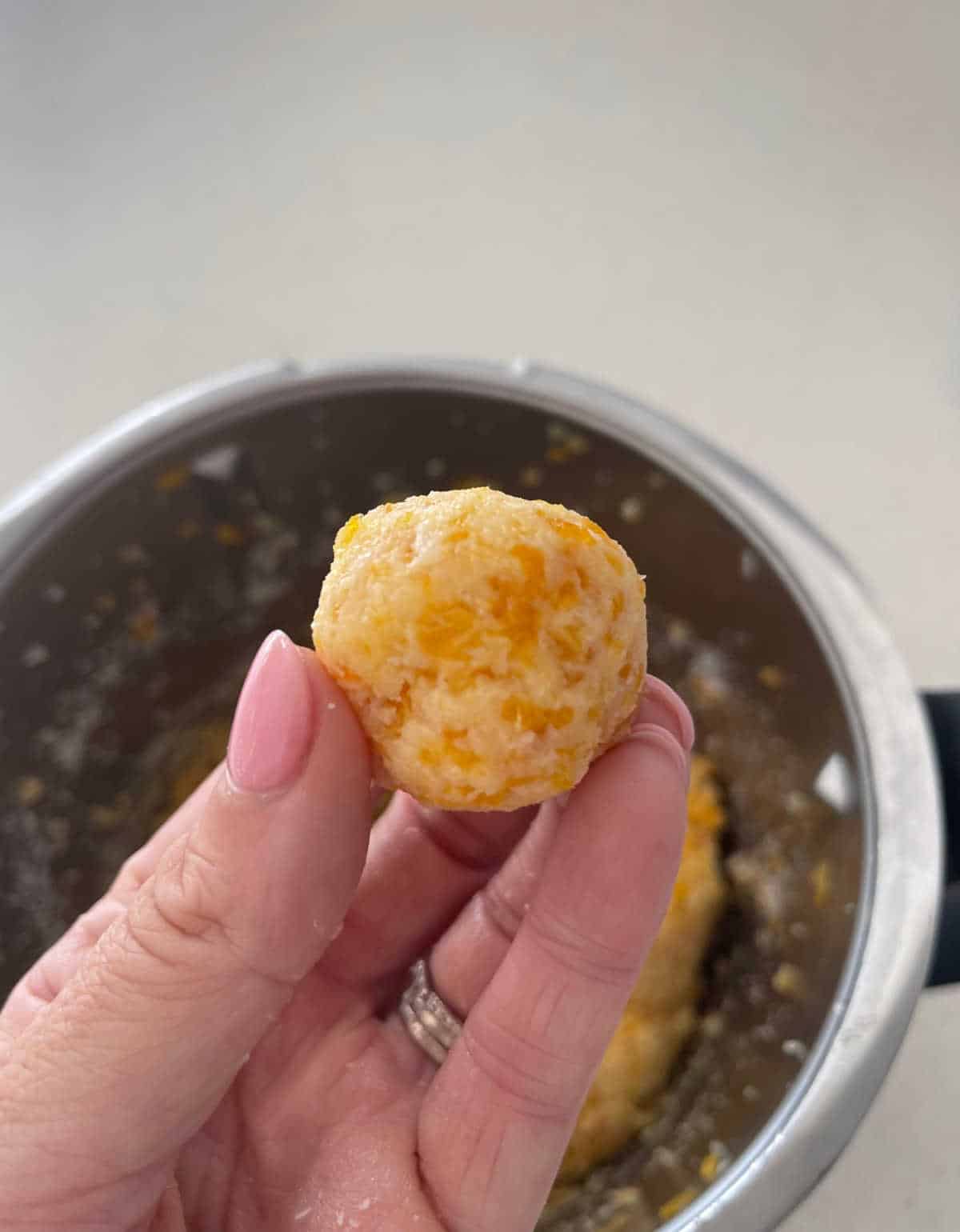 adult holding ball of apricot and coconut mixture.