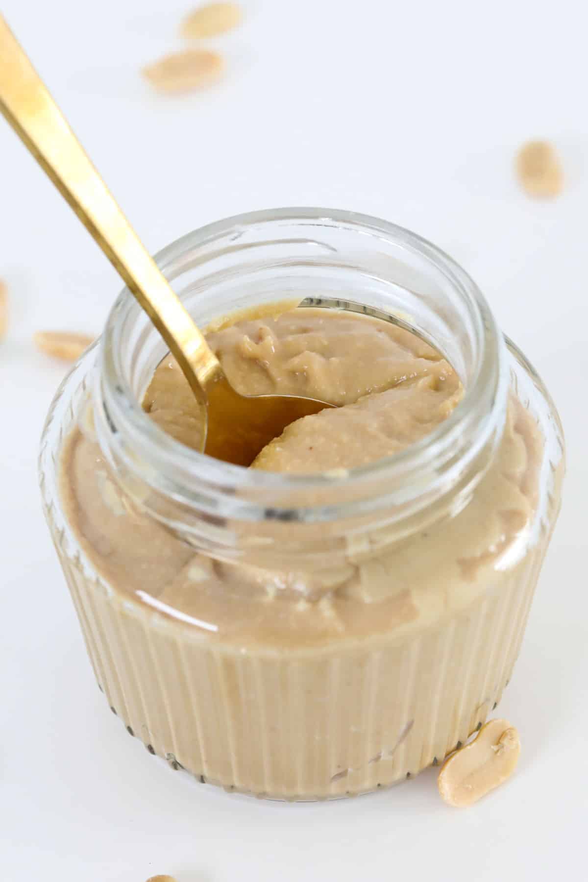 A gold spoon in a jar of homemade peanut butter.