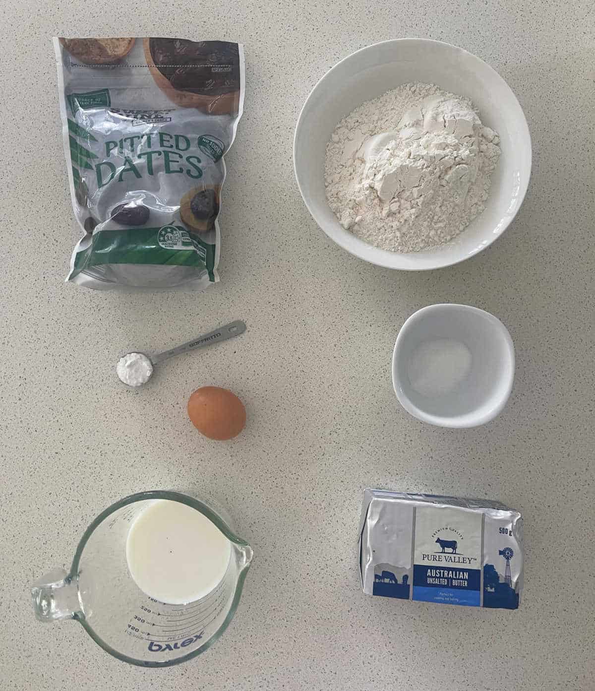 Ingredients to make Date Scones on a speckled bench top.