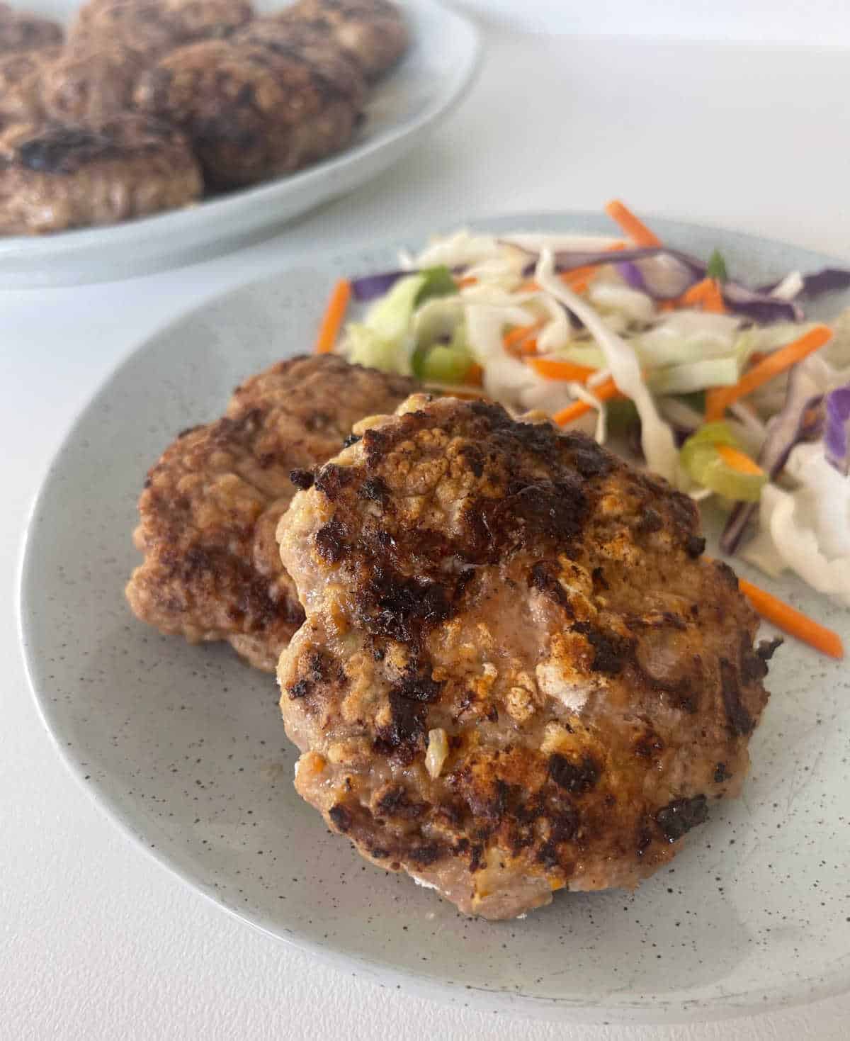 Two rissoles sitting on a green speckled plate with salad on the side.