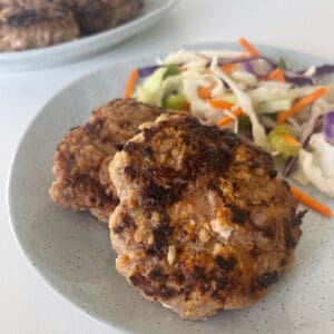 Two rissoles sitting on a green speckled plate with salad on the side.