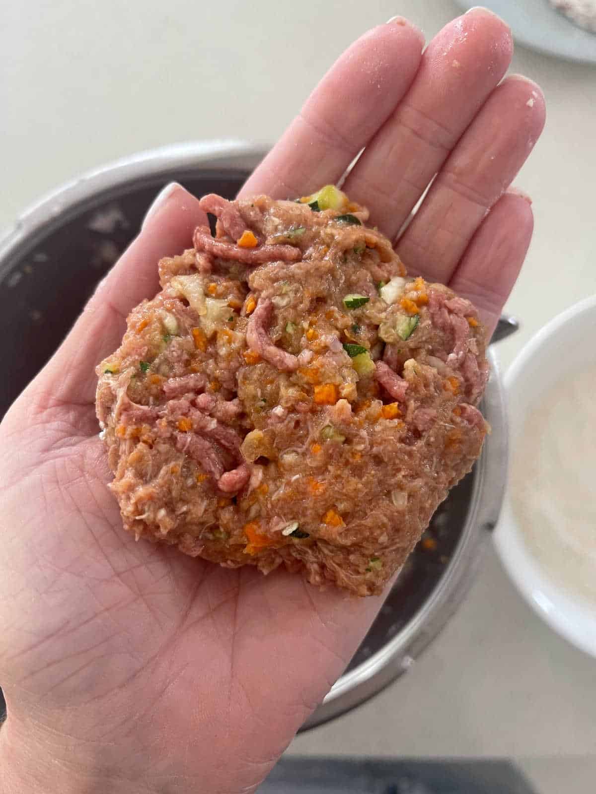 adult hand holding a rissole patty.