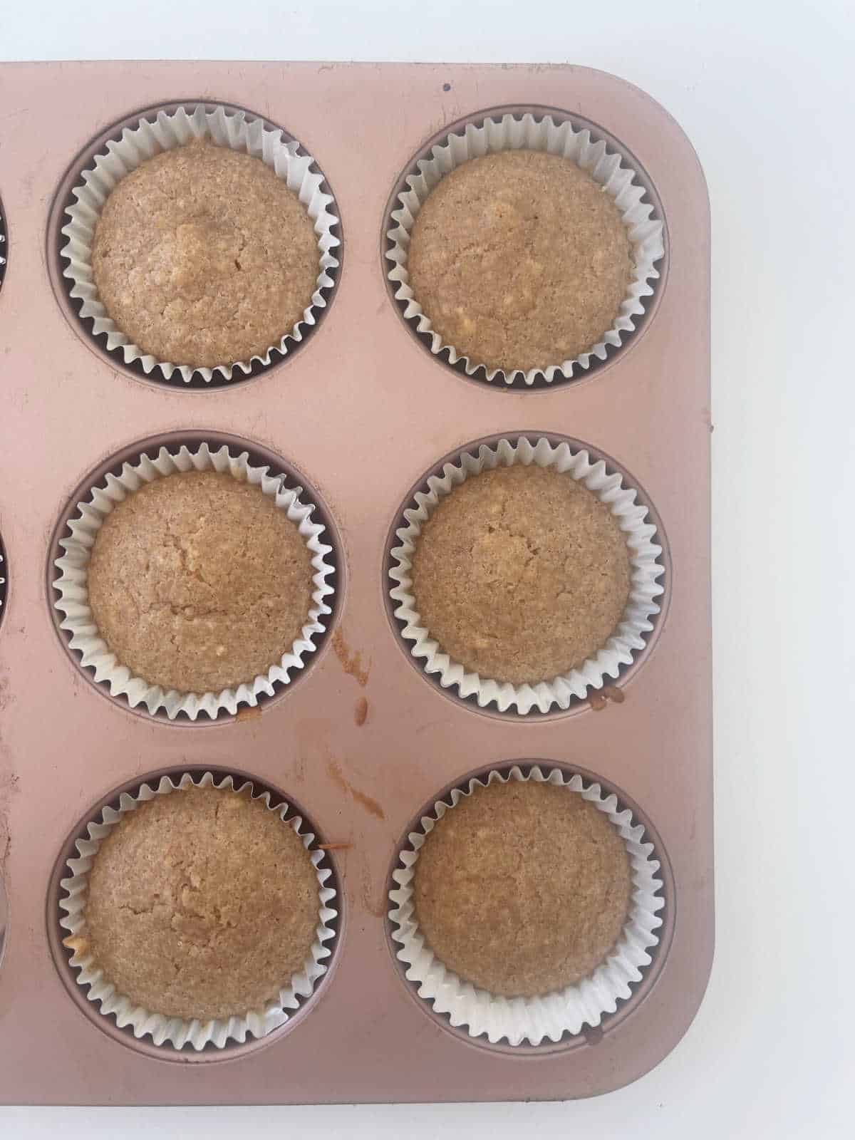 Baked APple and Cinnamon Muffins in a rose gold muffin tray.