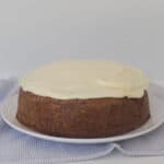 Carrot Cake topped with cream cheese frosting sitting on a white plate.