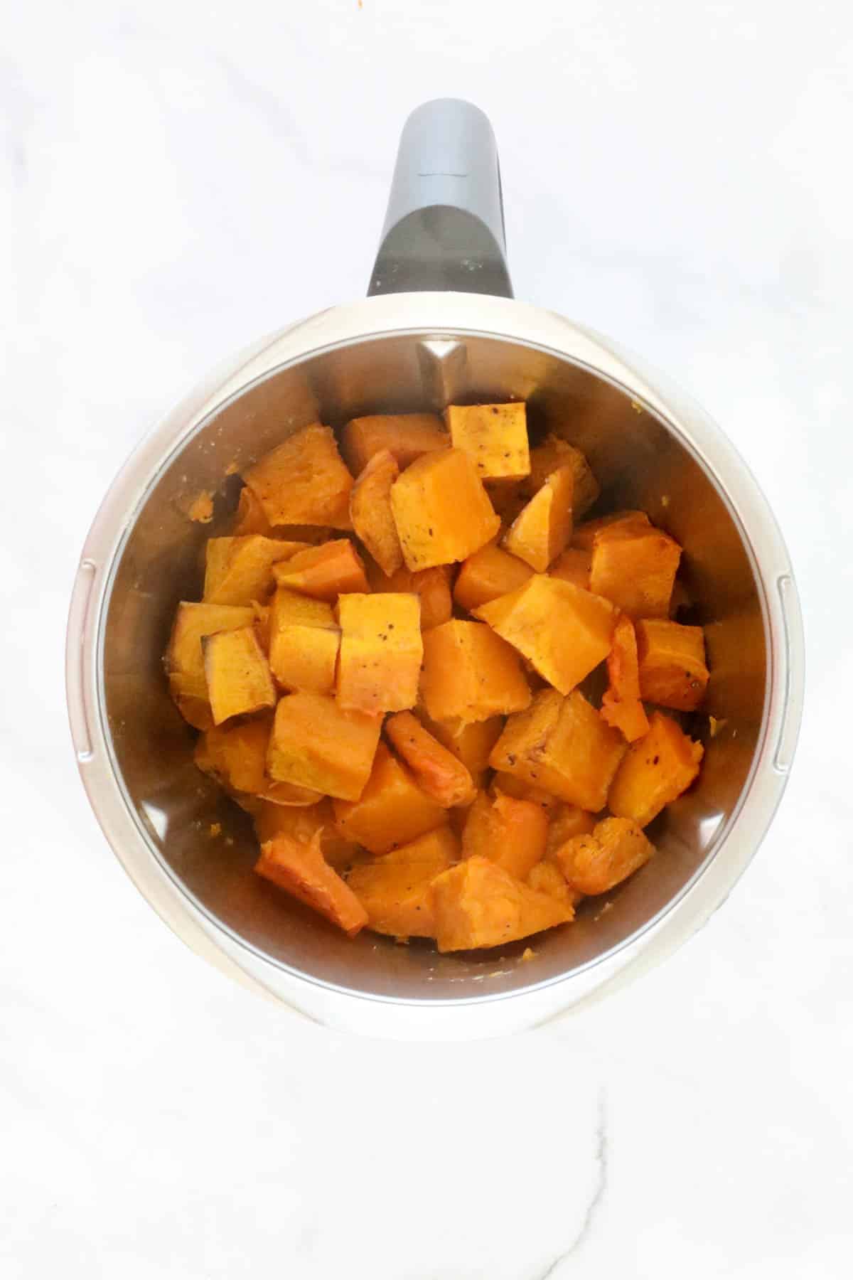 Roasted pumpkin pieces in a stainless jug.