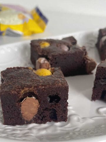 Pieces of Brownies with Easter egg stacked on a white plate.