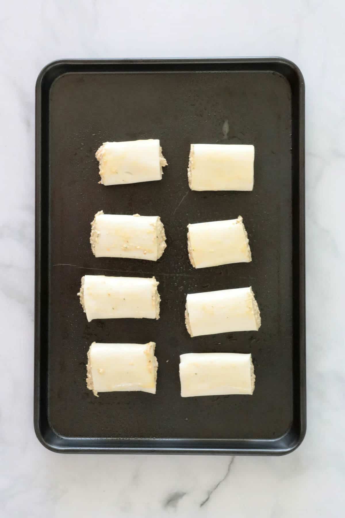 Sausage rolls on a baking tray.