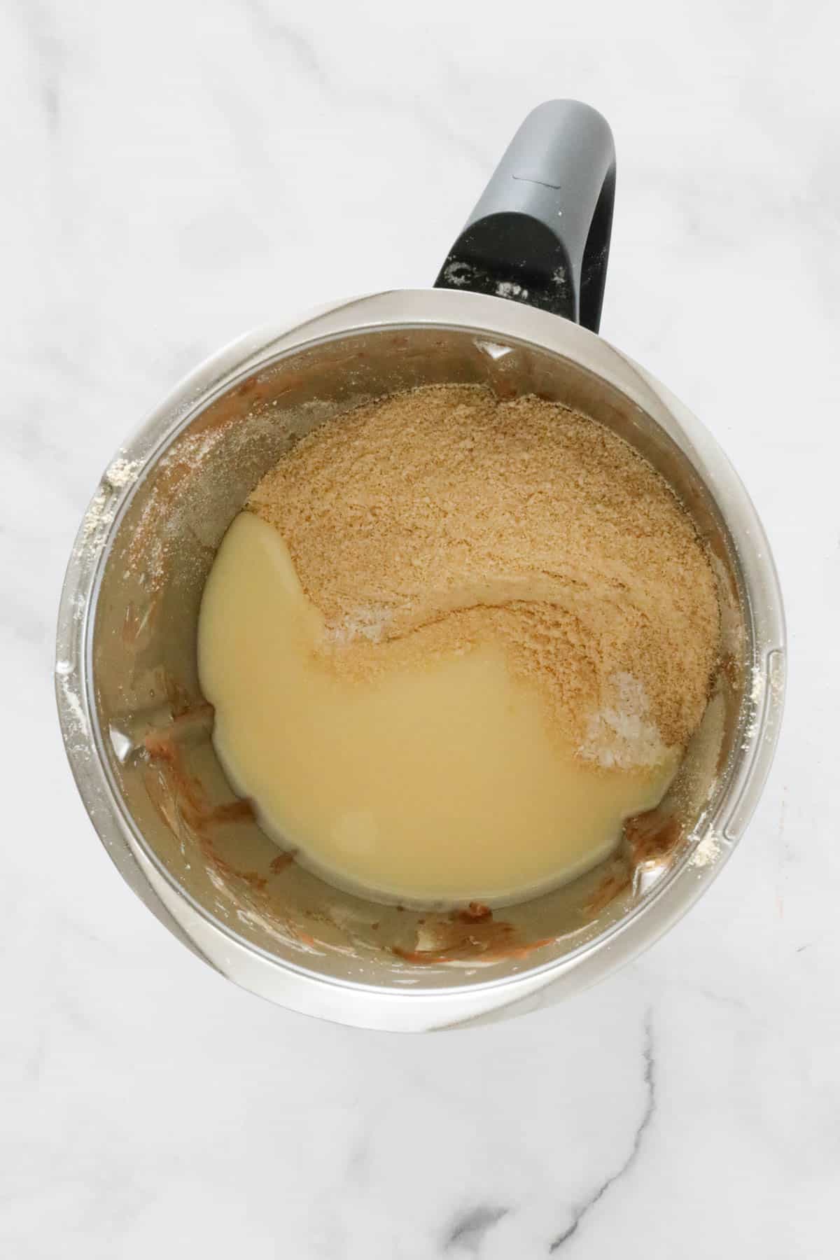 Crushed biscuits and sweetened condensed milk in a Thermomix.