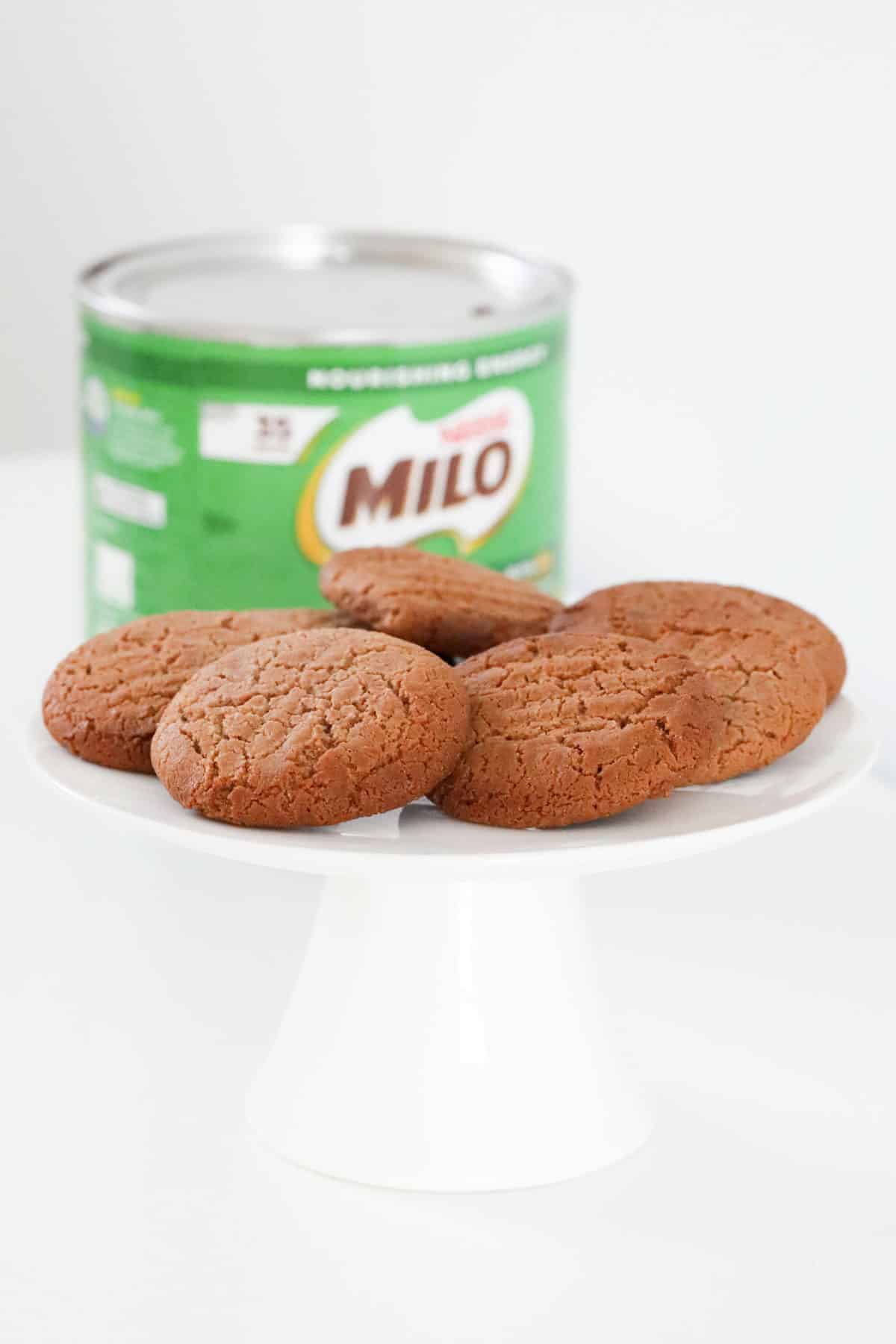 A Milo tin in the background of a plate of bicsuits.