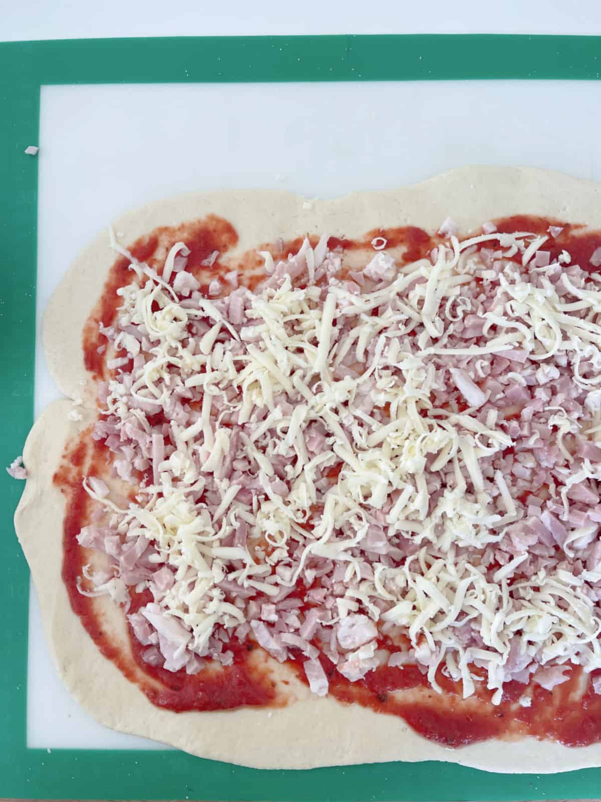 Scroll dough topped with pizza sauce, bacon pieces and cheese.