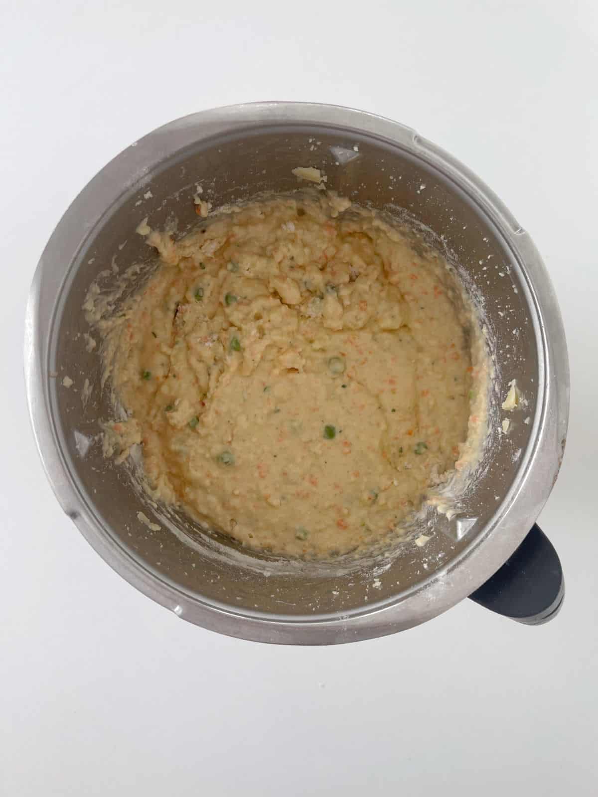 Vegetable Fritter mixture with peas and water added in a Thermomix bowl.