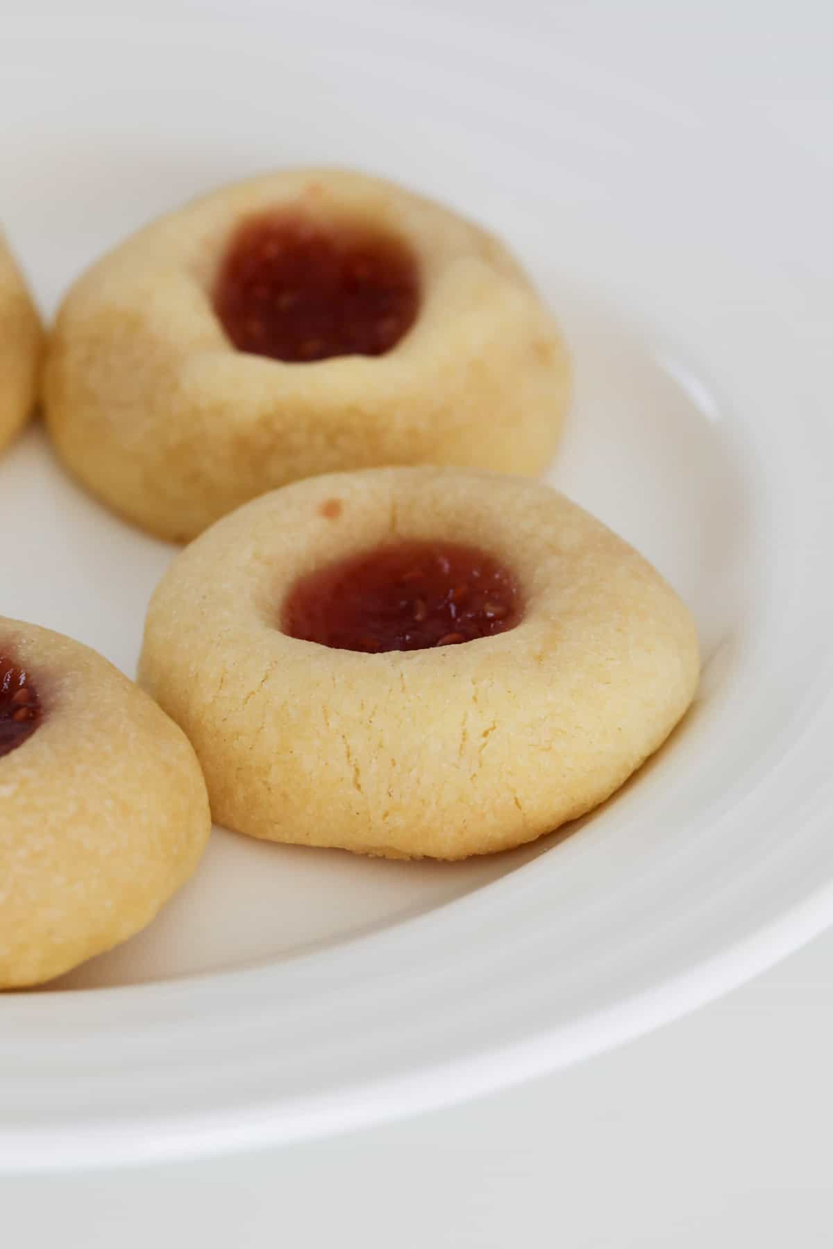 A plate of biscuits with jam in the middle.