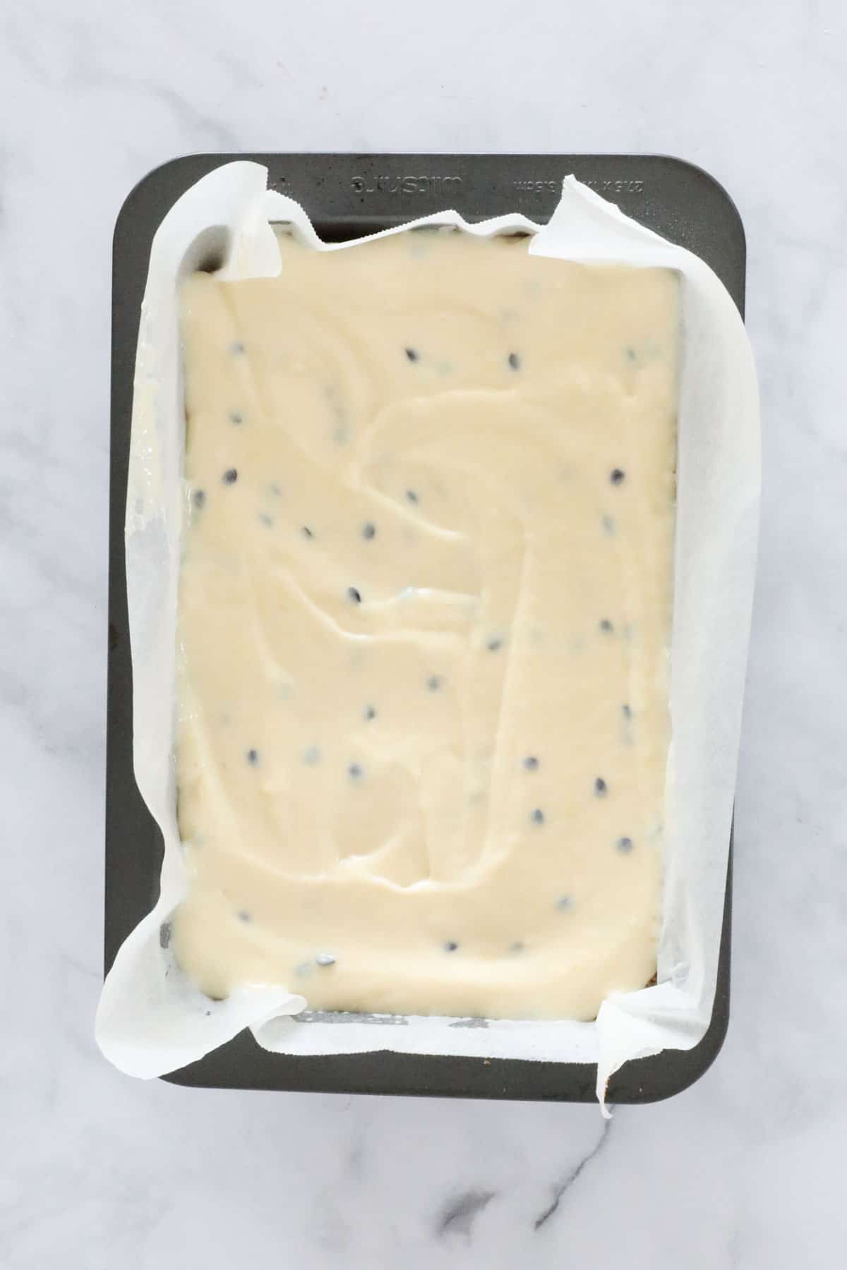 An overhead shot of a creamy unbaked slice in a tin.