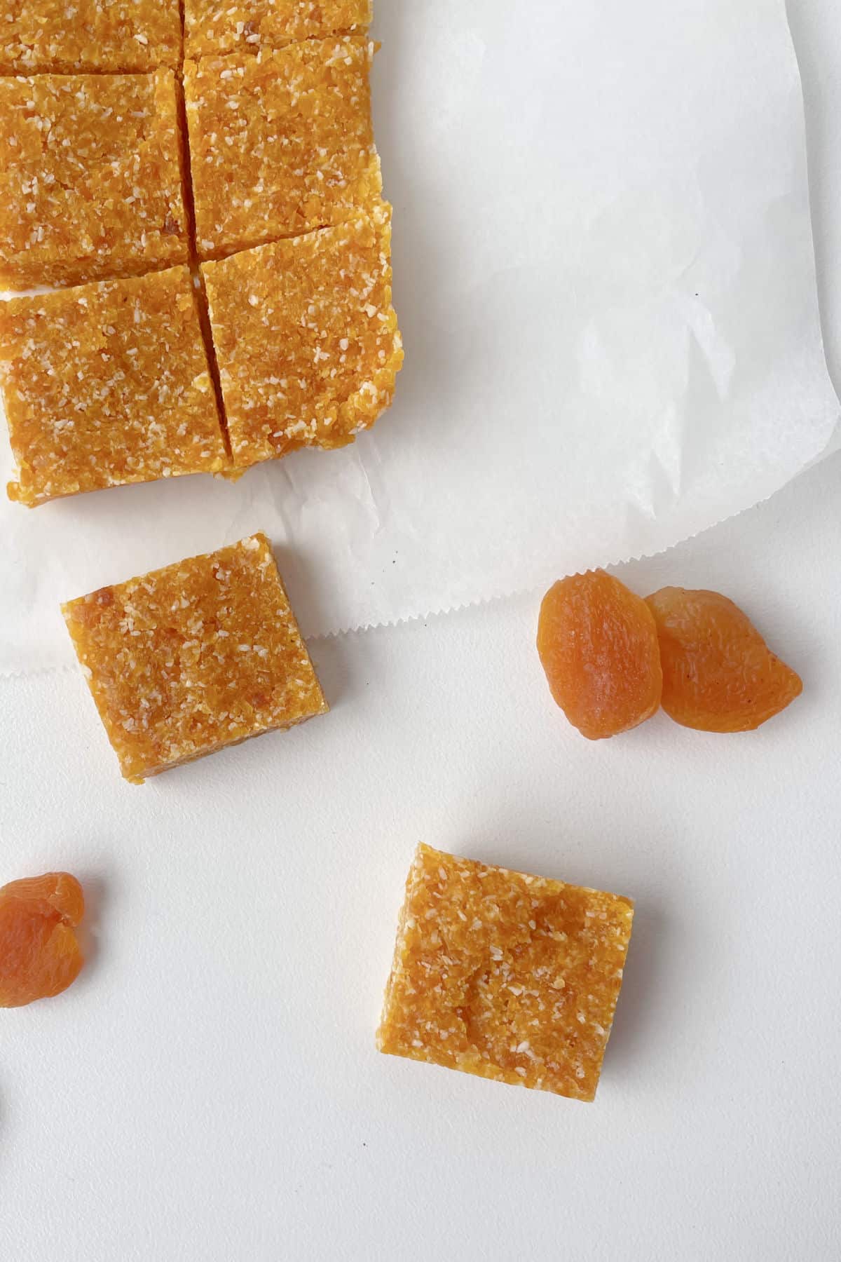 Overhead shot of Apricot and Coconut Slice on a white background with dried apricots spread around.