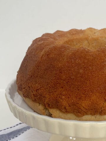 Cinnamon Cake baked in a bundt tin sitting on a cream cake stand.