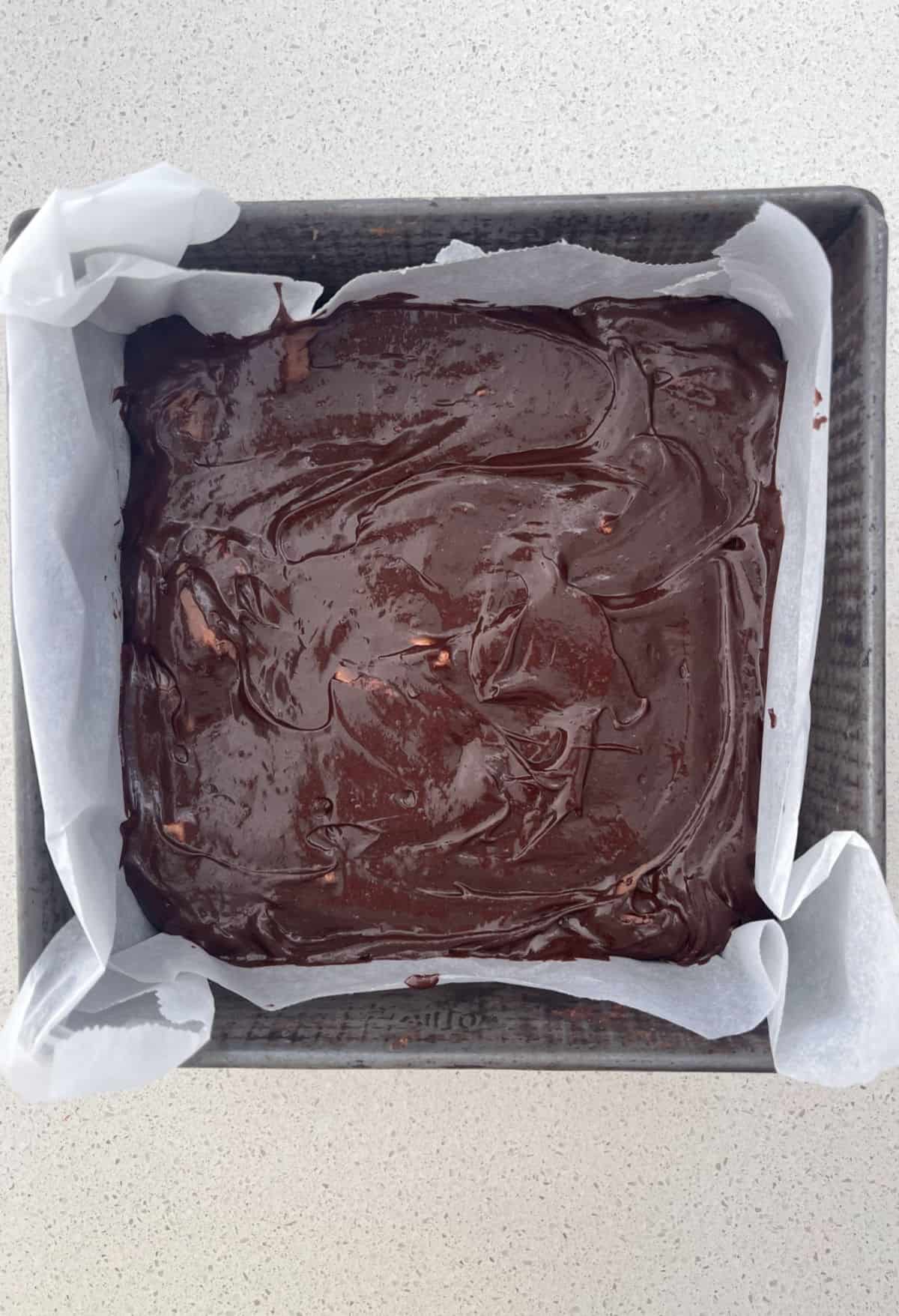 Mars Bar Brownie mixture in a baking dish lined with baking paper.