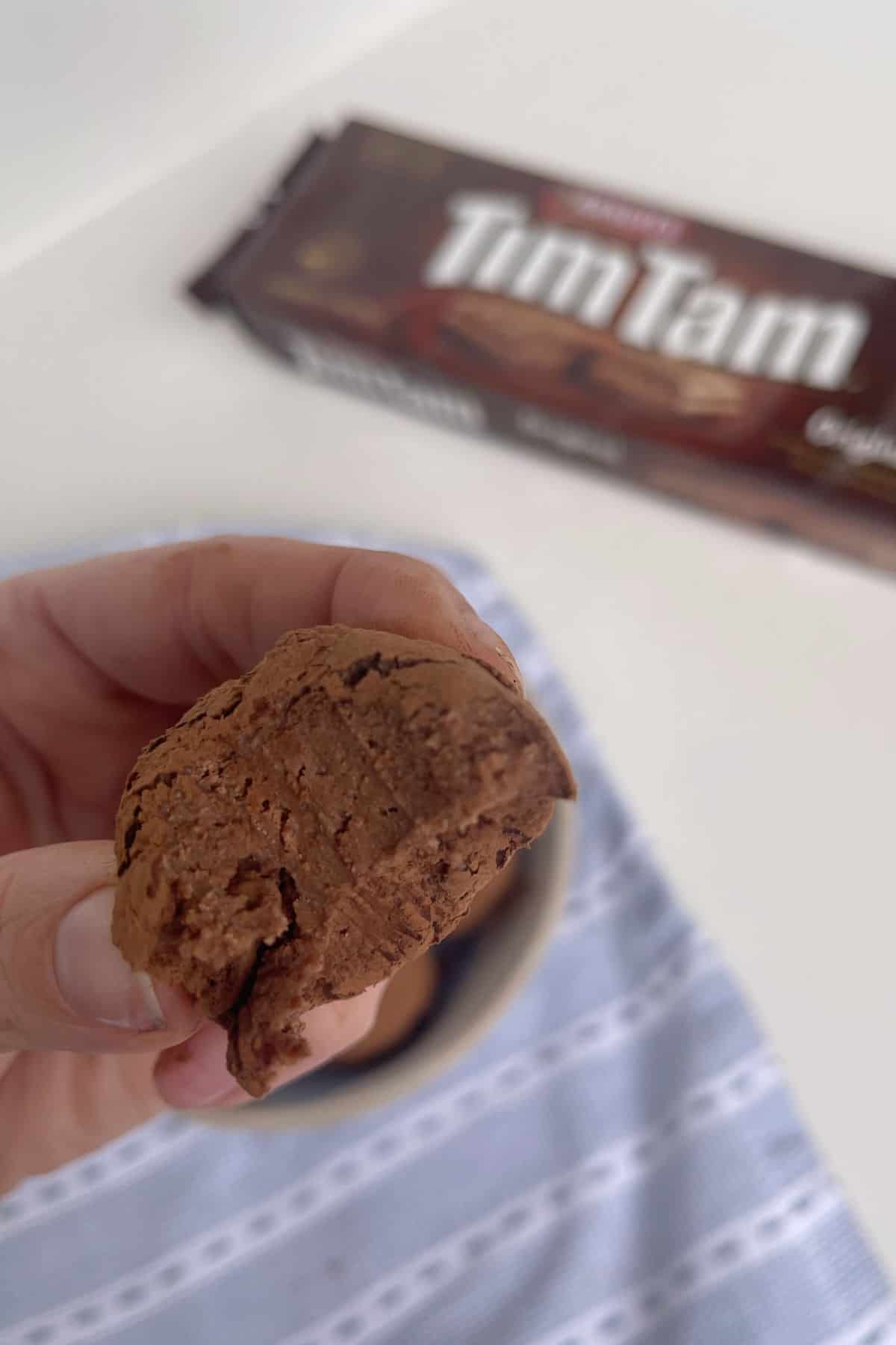 Tim Tam ball being held by an adult with a bite taken out of it.