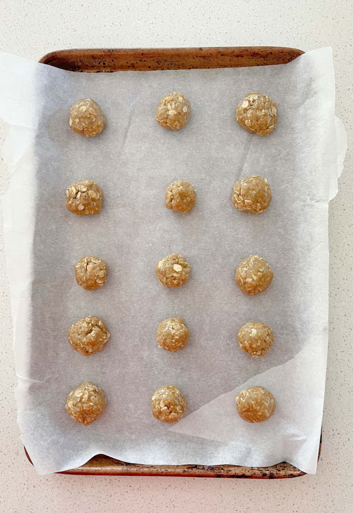 Anzac biscuit mixture rolled into balls on a baking tray.