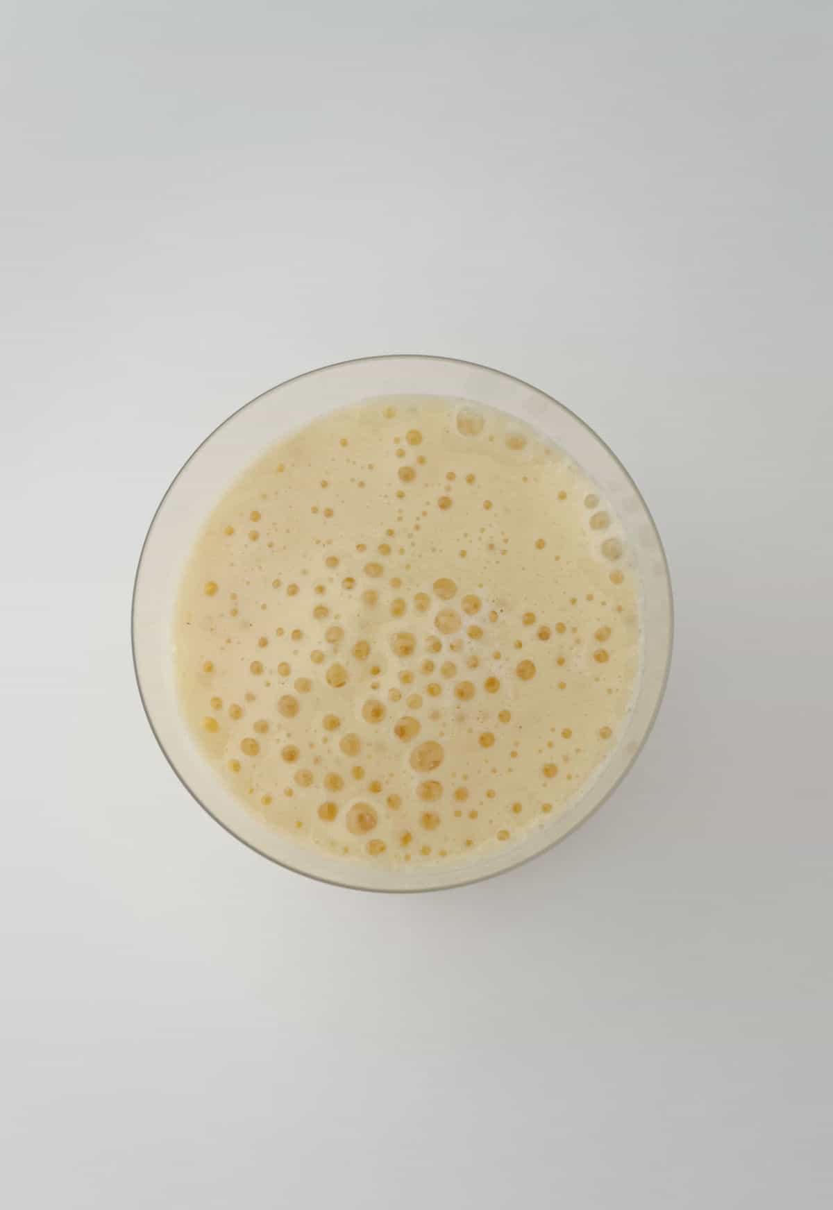 Overhead view of mango smoothie in a glass.