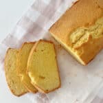 Overhead view of Sliced Pound Cake on a sheet of baking paper sitting on a pink and white check towel.