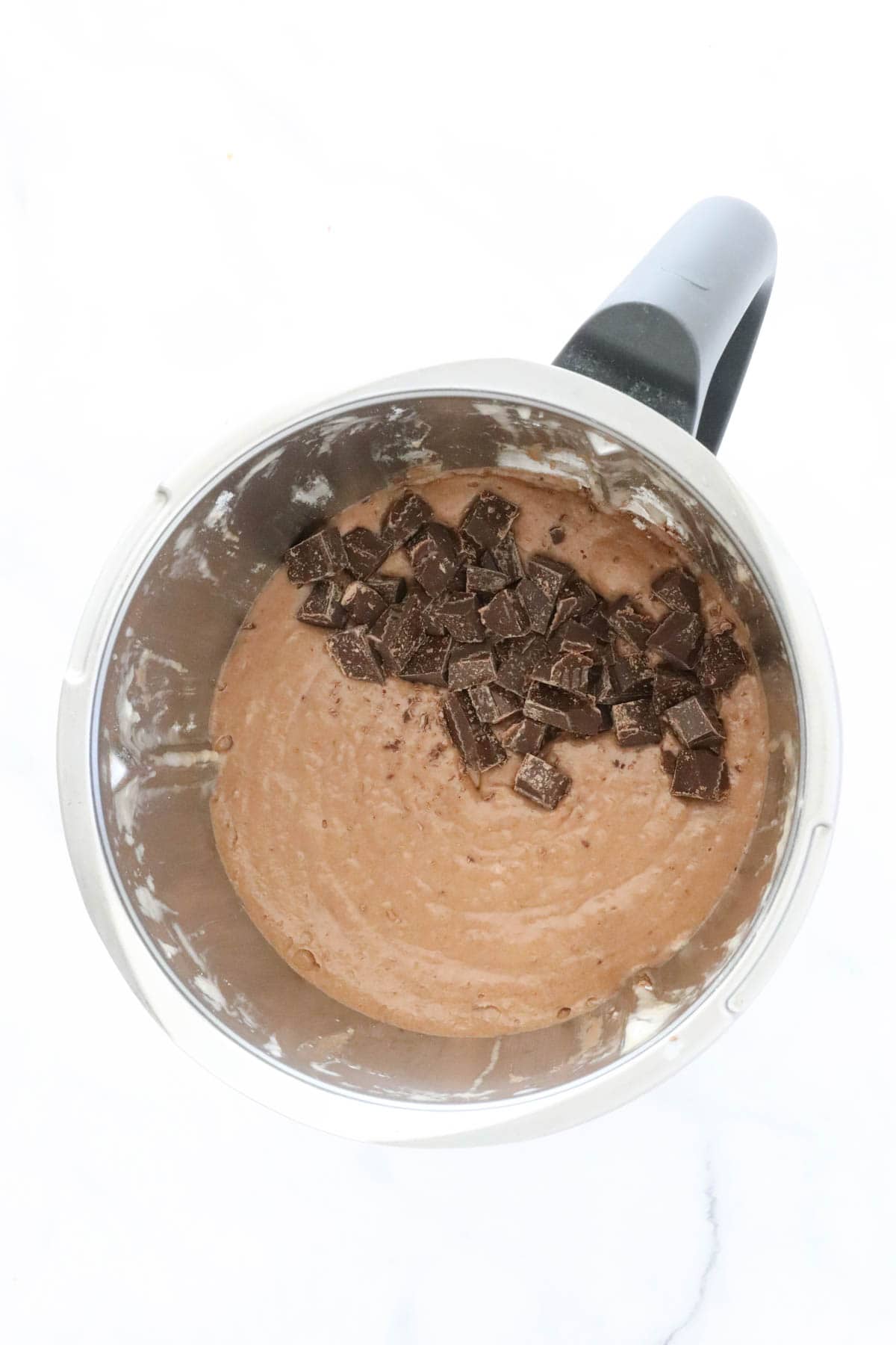 Chocolate chunks on top of chocolate muffin batter in a Thermomix.
