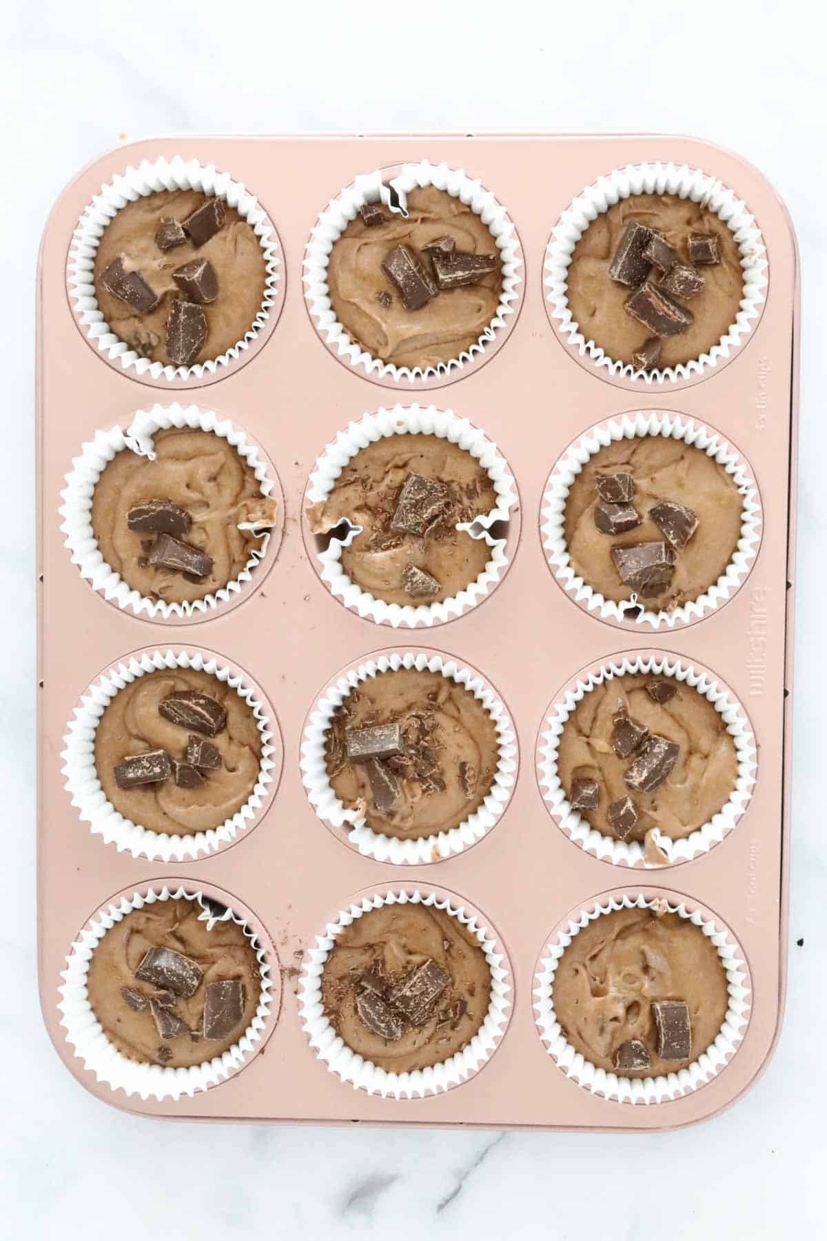 A muffin tray filled with chocolate muffin mixture.