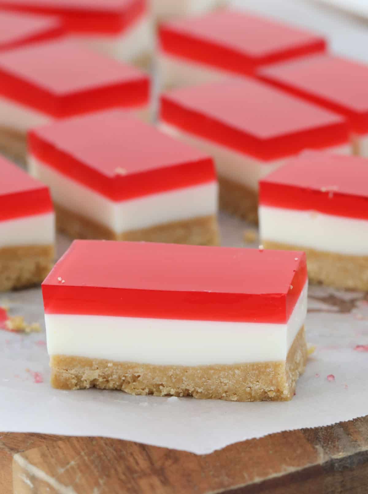 Pieces of strawberry jelly slice on a chopping board.
