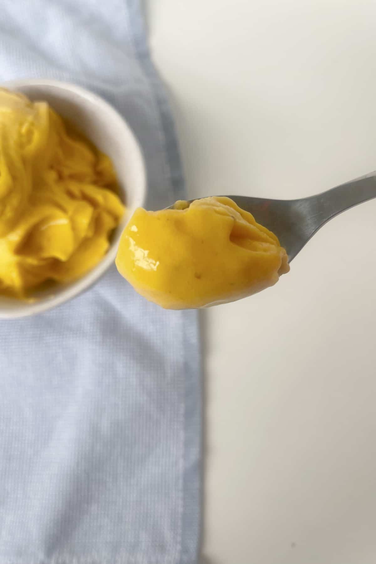 silve spoon scooping up mango nice cream.